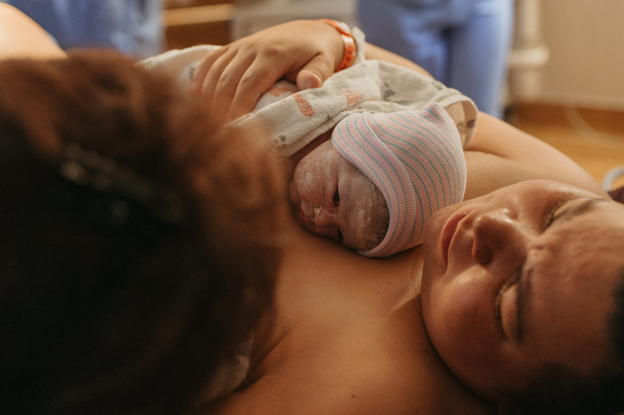 Newly postpartum mom with newborn baby laying across chest after being born
