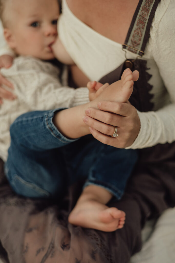 Toddler-nursing-while-mom-is-holding-baby's -oot-Longmont-Maternity-&-In-Home-Newborn-Photographer