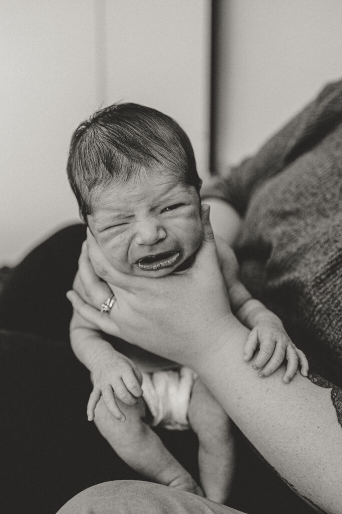 Longmont Newborn crying while being burped due to being uncomfortable during in home newborn session with alexis adkins photography