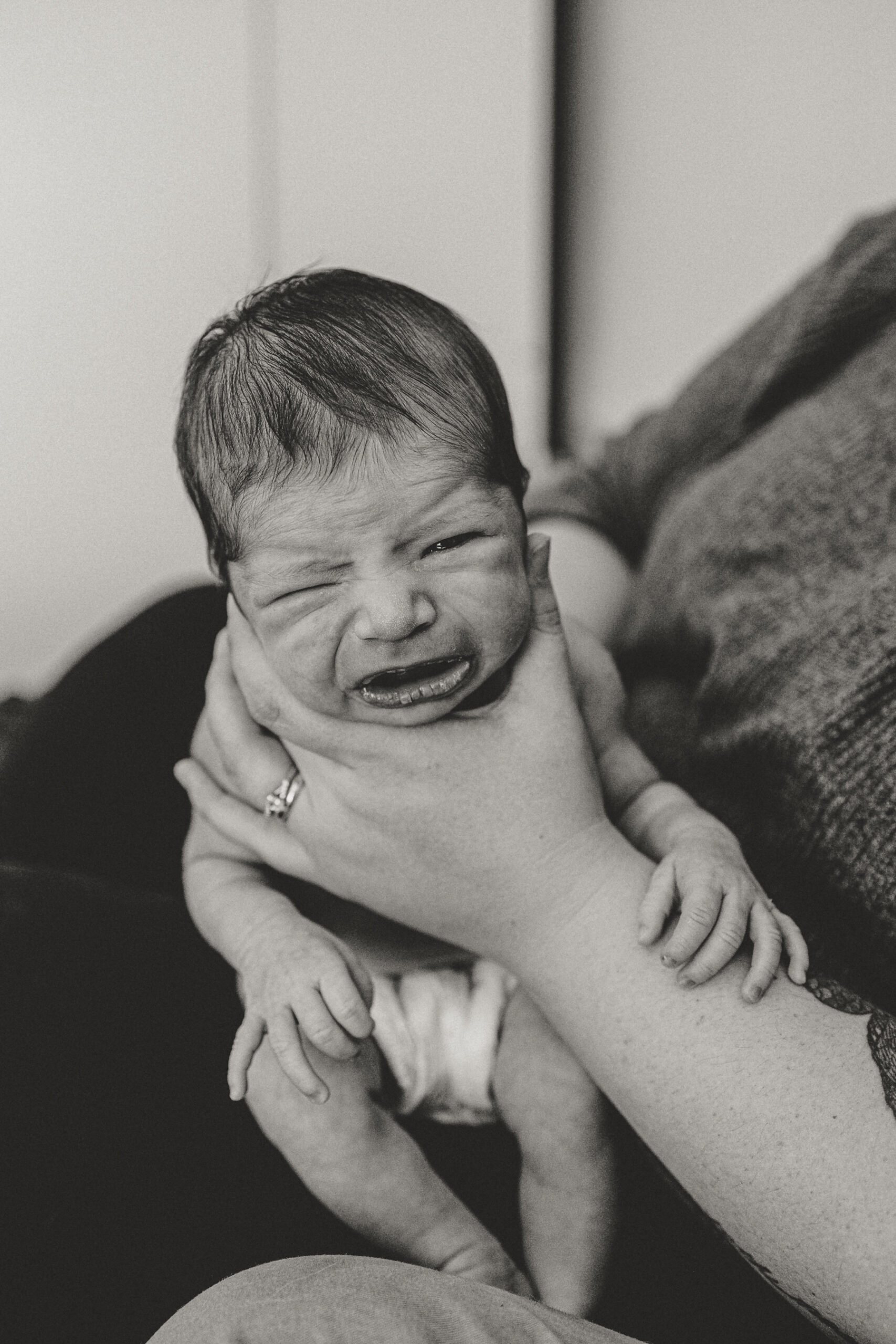 Longmont Newborn crying while being burped due to being uncomfortable during in home newborn session with alexis adkins photography